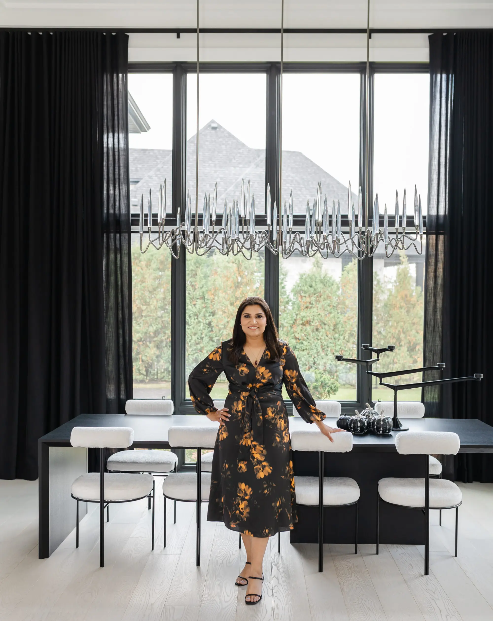 Ravi Gill, Oakville realtor, standing beside a black dining table in a staged modern home