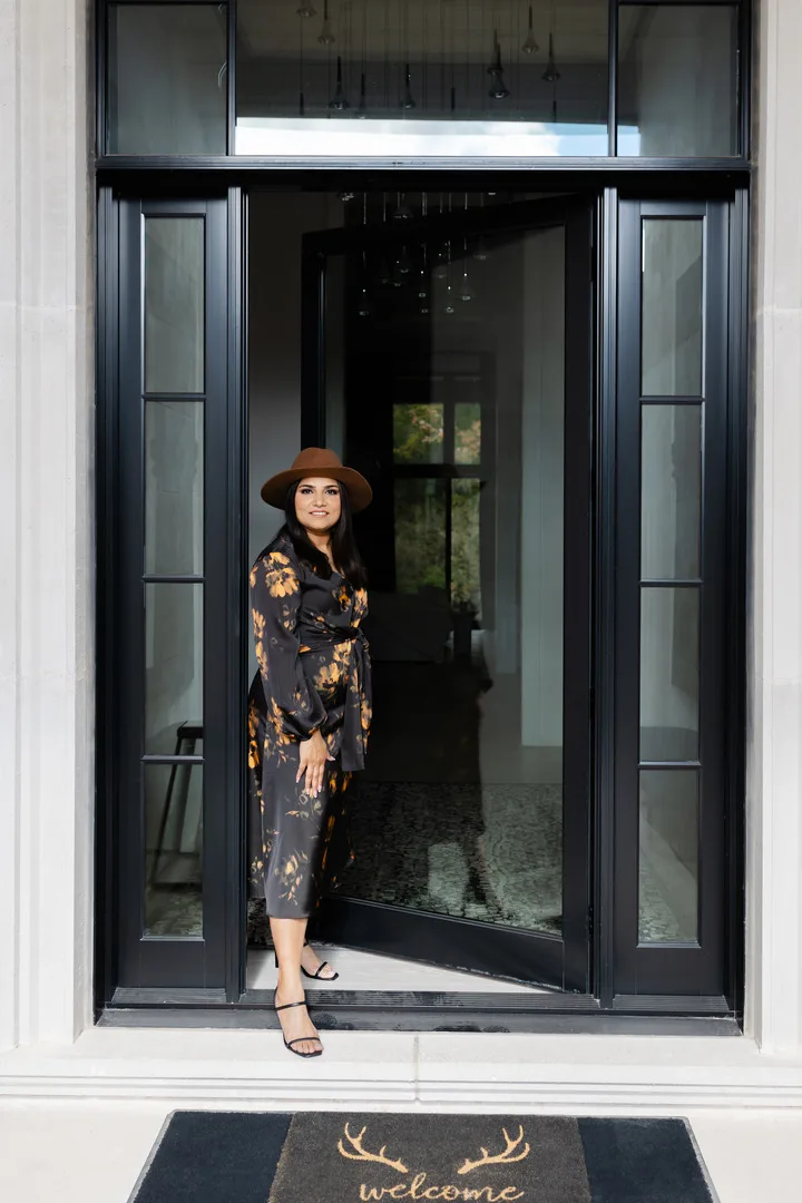 Ravi Gill, Oakville realtor, standing in the open black front door of a modern home