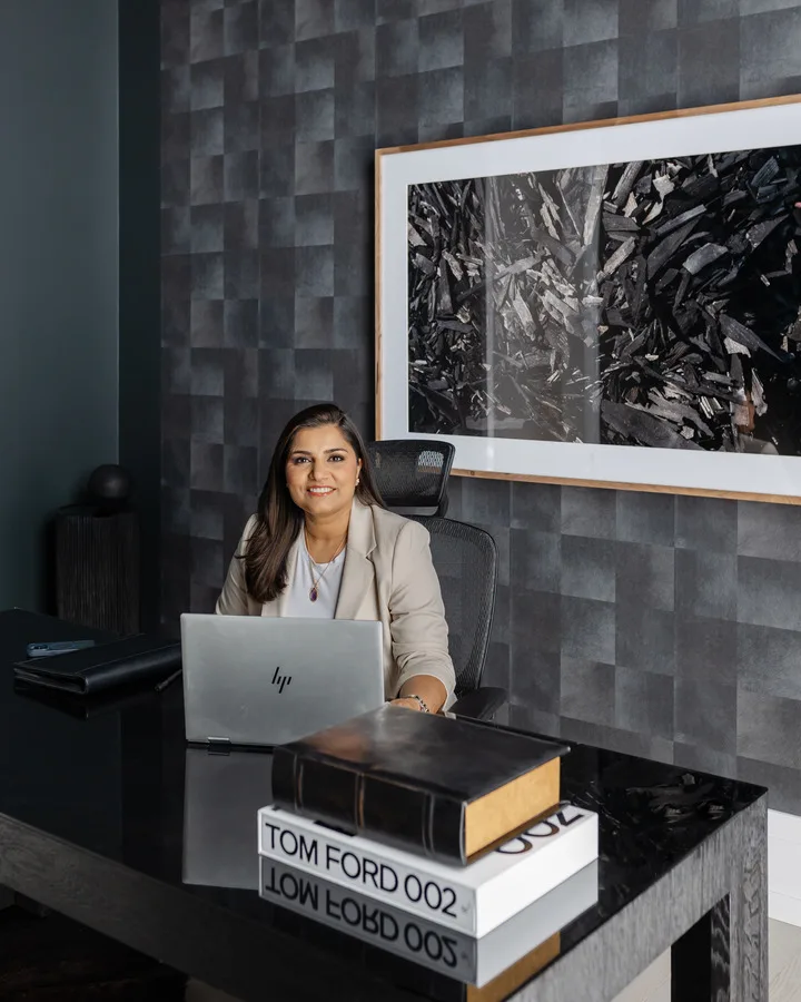 Ravi Gill working at a black desk with a laptop in a dark, textured home office