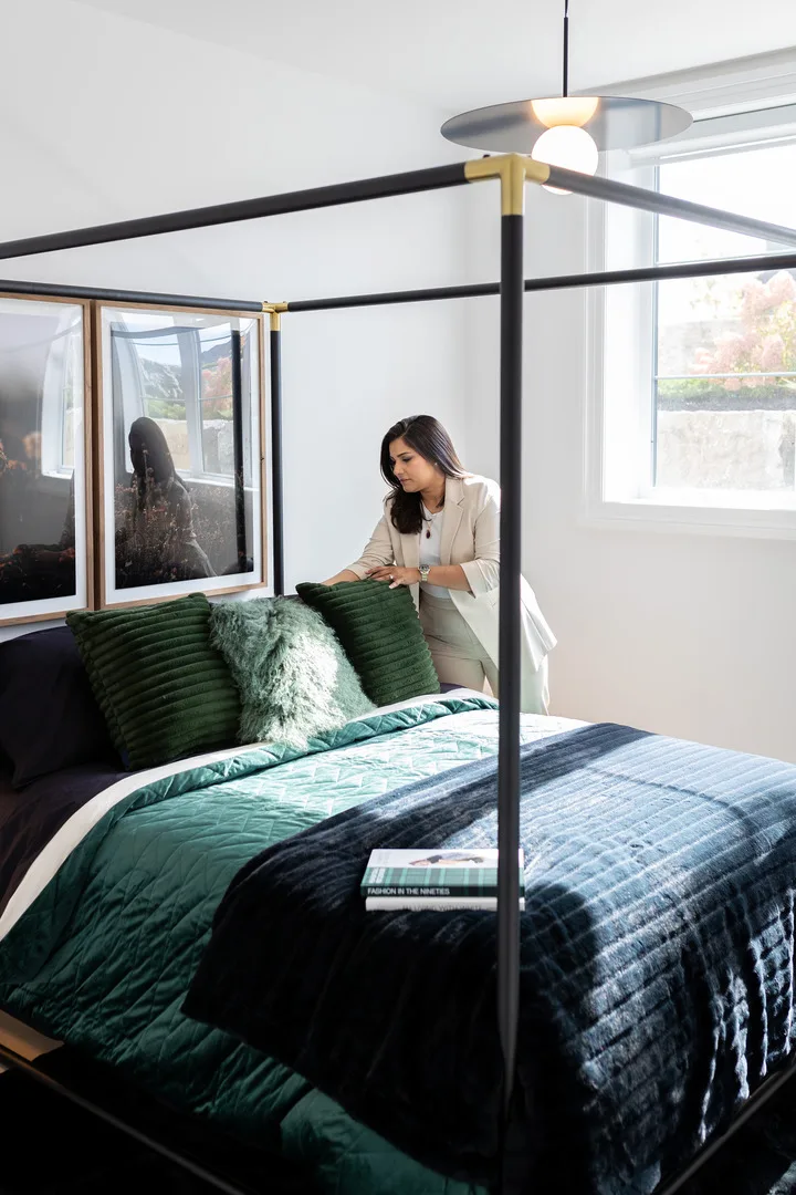 Ravi Gill seated on a four-poster bed with green bedding in a bright primary bedroom